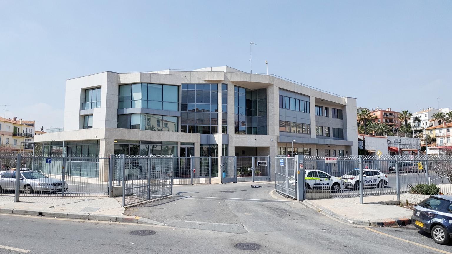 Umzäuntes Verwaltungsgebäude mit Polizeifahrzeugen in einer spanischen Küstenstadt