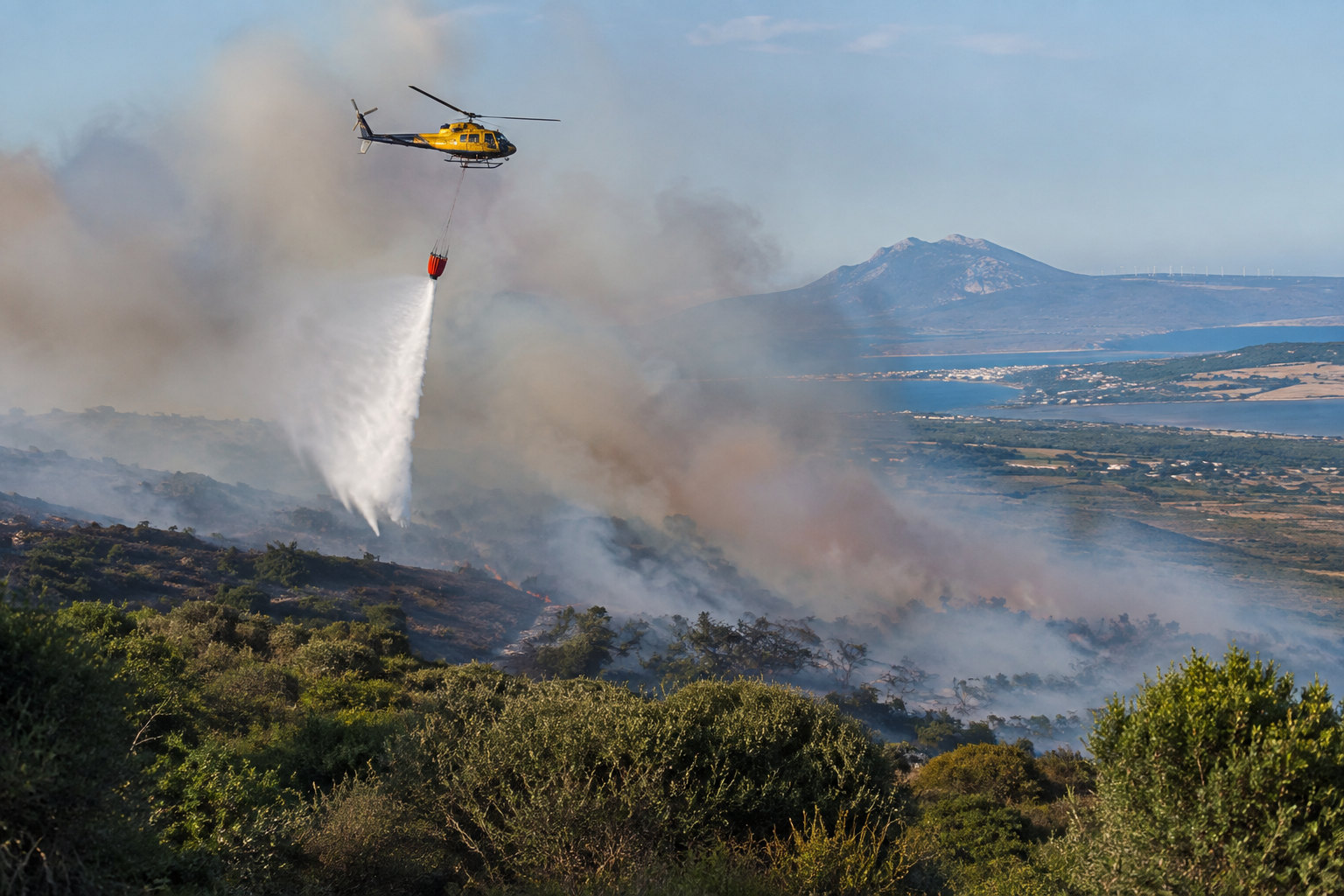 Löschhubschrauber über einem Waldbrandgebiet mit Buschland zwischen Tarifa und Los Barrios