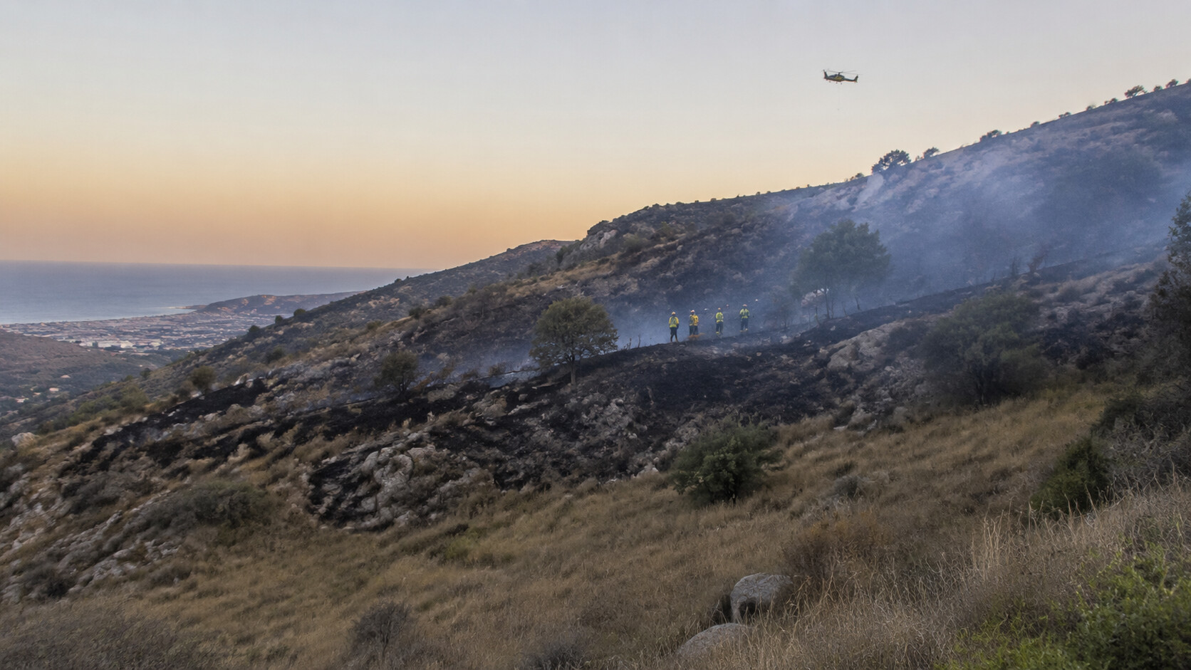 Verbrannter Hang, leichter Rauch und Einsatzkräfte nach einem Waldbrand bei Molvízar