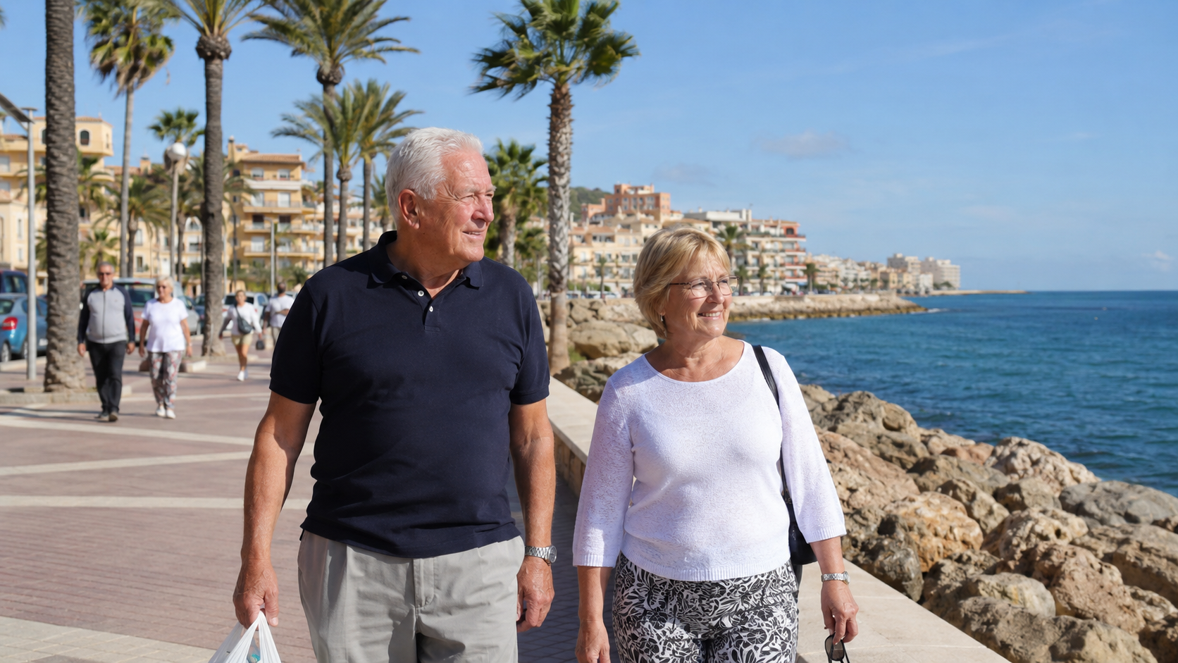 Älteres deutsches Paar spaziert an einer sonnigen Küstenpromenade in Spanien